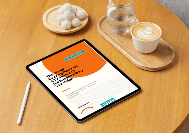 Tablet displaying “The Creator Economy Playbook” by Jonathan Glazier on a wooden table next to a coffee, water glass, and snacks.