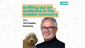A smiling man wearing glasses and a black turtleneck stands beside a fluffy dog, with text that reads “Sniffing out an audience in the creator economy – TV v The Creator Economy” over a background of media-related icons.