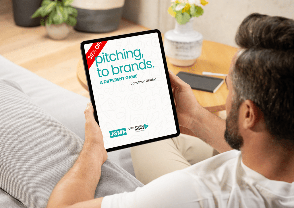 A man reads a digital PDF titled Pitching to Brands: A Different Game on a tablet, showing a 30% off banner. The guide is focused on branded entertainment strategy.